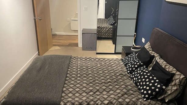 A bedroom with a bed, a bedside table, a mirror, and a wardrobe. - Charming 2-bed Apartment in Bow, London (London)
