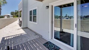 A covered outdoor area with a wooden deck, a sliding glass door, and a small rug. - Perdido Dunes 29 by Liquid Life (Orange Beach)