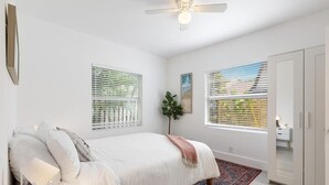 A bedroom with a bed, a ceiling fan, two windows with blinds, a plant, and a wardrobe. - Private 2 Bedroom Apartment Near Beach (Fort Lauderdale)