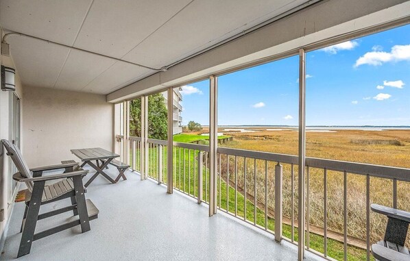 Un balcon donnant sur un champ et un bâtiment situé au loin.