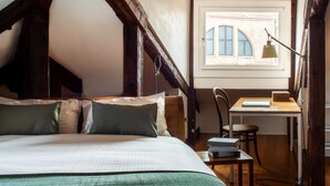 Une chambre à coucher avec un lit, un bureau et une chaise. Il y a une fenêtre donnant sur l’extérieur.