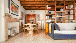 Una sala de estar acogedora con techo de madera, chimenea, mesa de comedor con sillas, sofá y estantería.