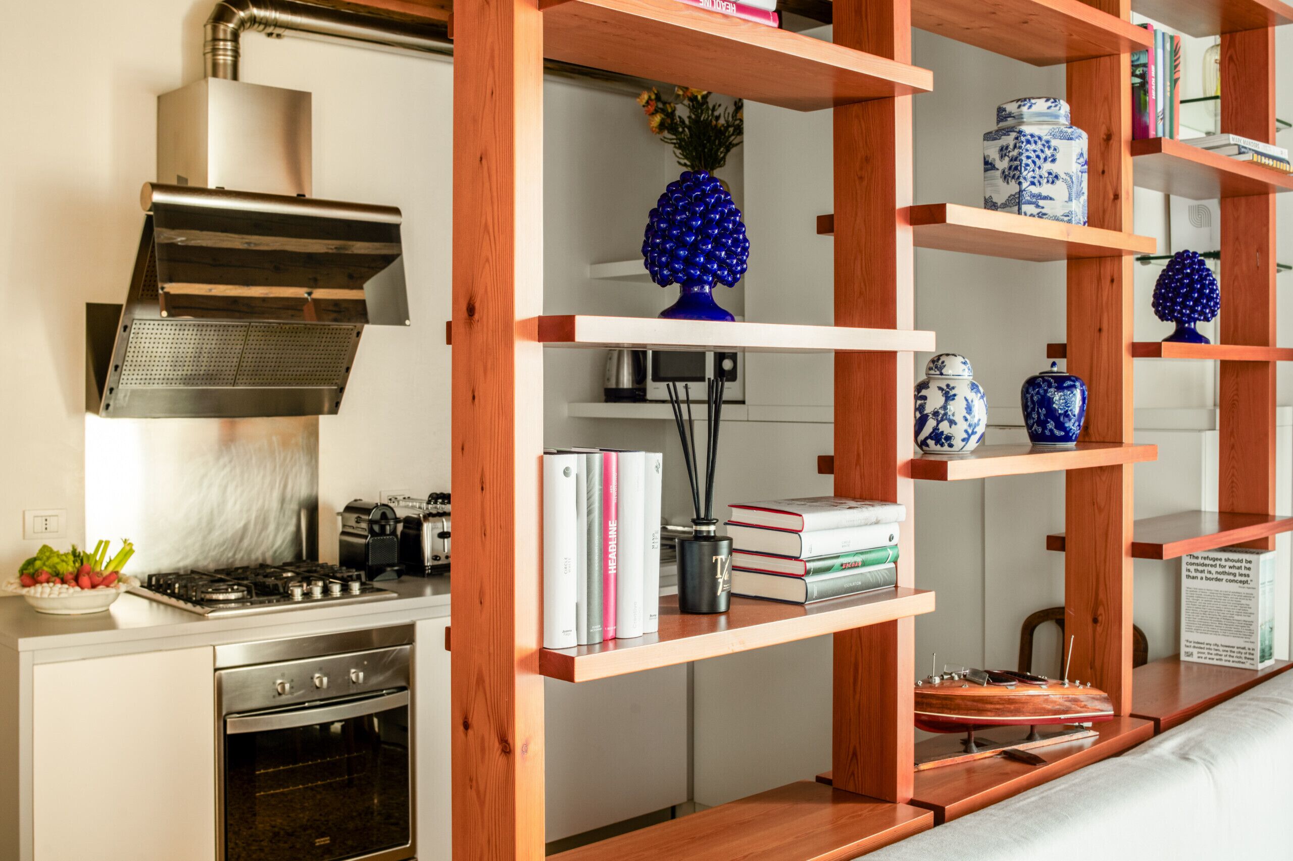 Una cocina con estantes de madera, una estufa y una campana extractora.