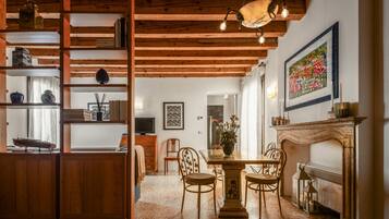 Un comedor acogedor con una mesa y sillas de madera, una estantería y una chimenea.