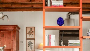 Una sala de estar acogedora con un aparador de madera, una mesa de comedor con sillas, un sofá azul con cojines y una estantería con libros y adornos.