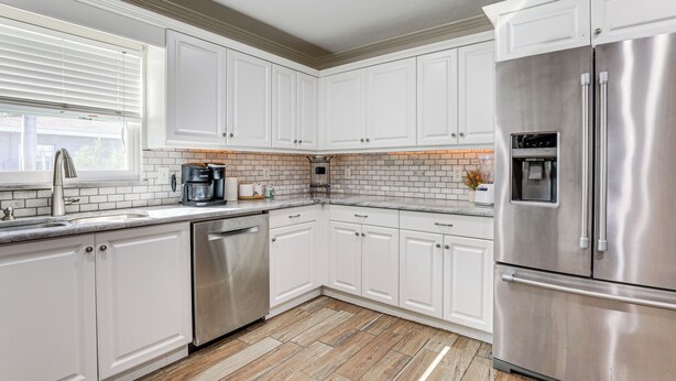 A modern kitchen with white cabinets, stainless steel appliances, and a tiled backsplash. - Pet-friendly Home w/ Heated Pool in Bradenton (Bradenton)