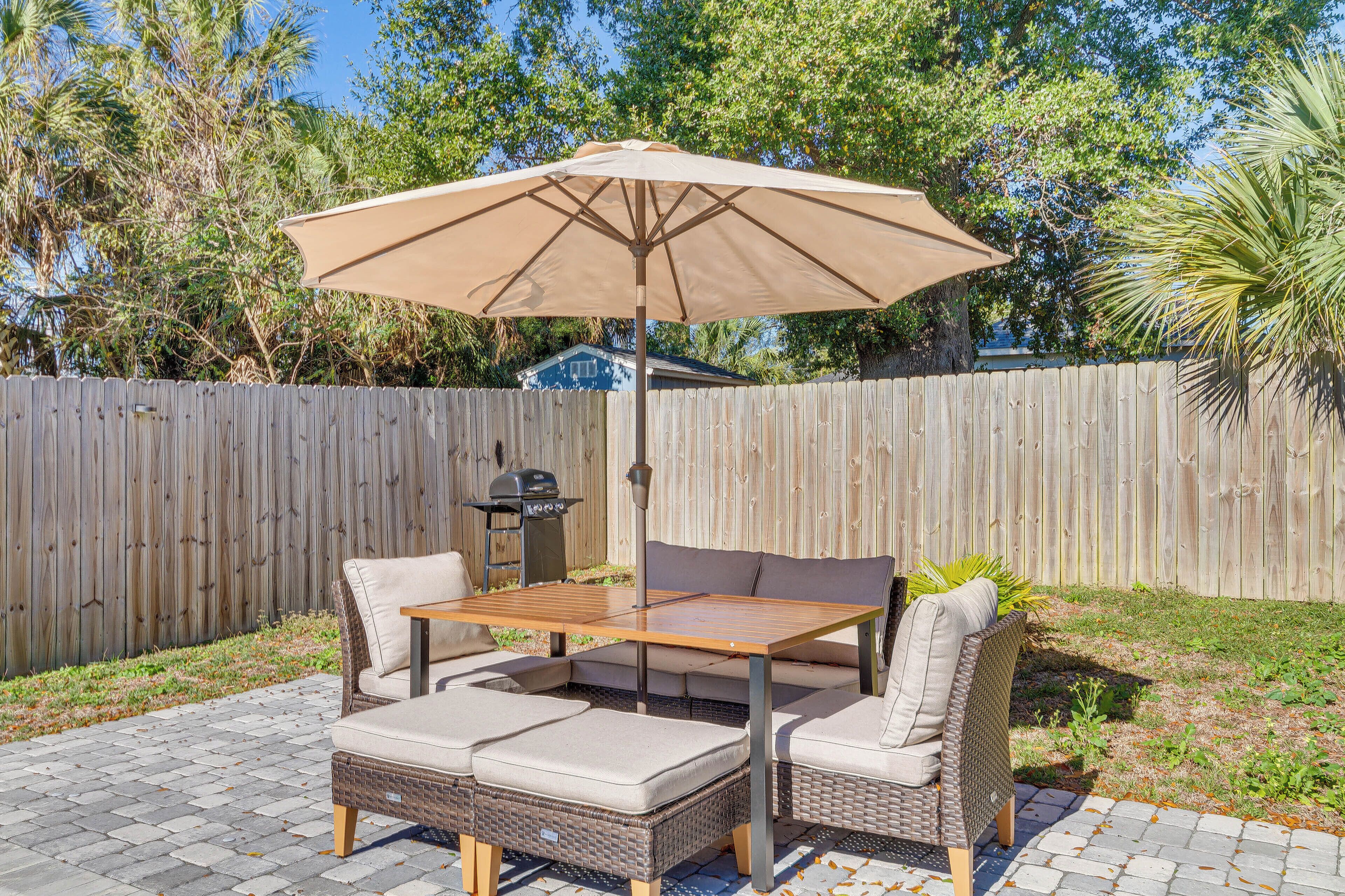 Een terras met een tafel, stoelen, een parasol en een houten hek op de achtergrond.