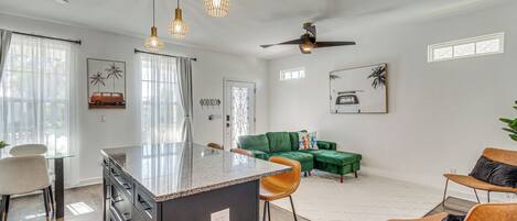 Una cocina moderna con una isla central, taburetes de bar e iluminación colgante.