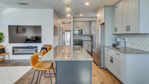 A modern kitchen with a central island, stainless steel appliances, and light grey cabinetry. - Modern Pensacola Vacation Home w/ Private Pool! (Pensacola)