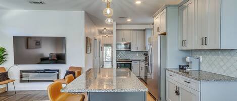 Una cocina moderna con una isla central, electrodomésticos de acero inoxidable y armarios color gris claro.