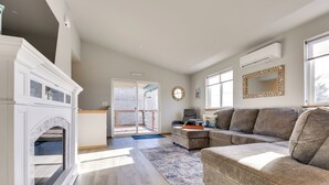 A spacious living room with a fireplace, a large sectional sofa, and a view through a glass door to an outdoor balcony. - Canal-front Home in Ocean Shores w/ Dock & Views! (Ocean Shores)