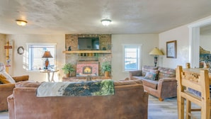 A cozy living room with a brick fireplace, comfortable seating, and a rustic ceiling. - Downtown Del Norte Home Near Hiking & Fishing! (Del Norte)