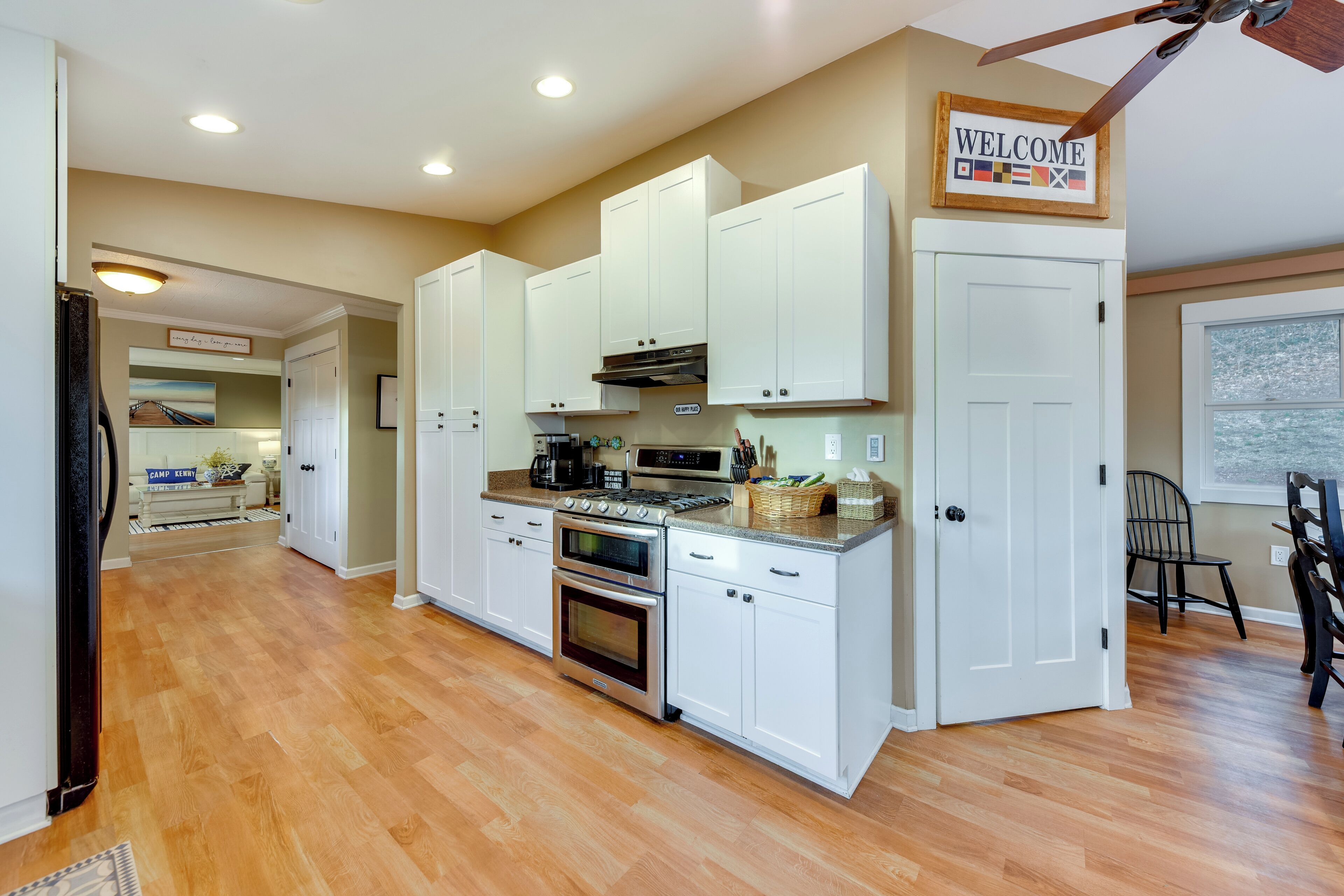 A kitchen with white cabinets, a stove, and a ceiling fan.