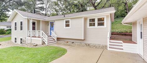 A single-story house with a front porch, a blue door, and a small set of stairs leading to the entrance.