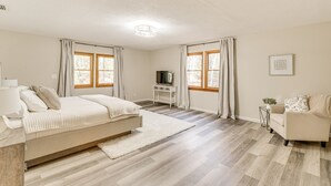 Ein Schlafzimmer mit einem Bett, einem Schreibtisch, einem Sessel und einem Fernseher.