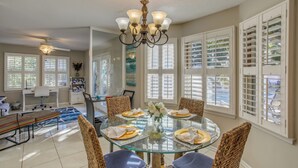 A dining area with a glass table, wicker chairs, and a chandelier. - Near the Sand! Myrtle Beach Home w/ Saltwater Pool (Myrtle Beach)