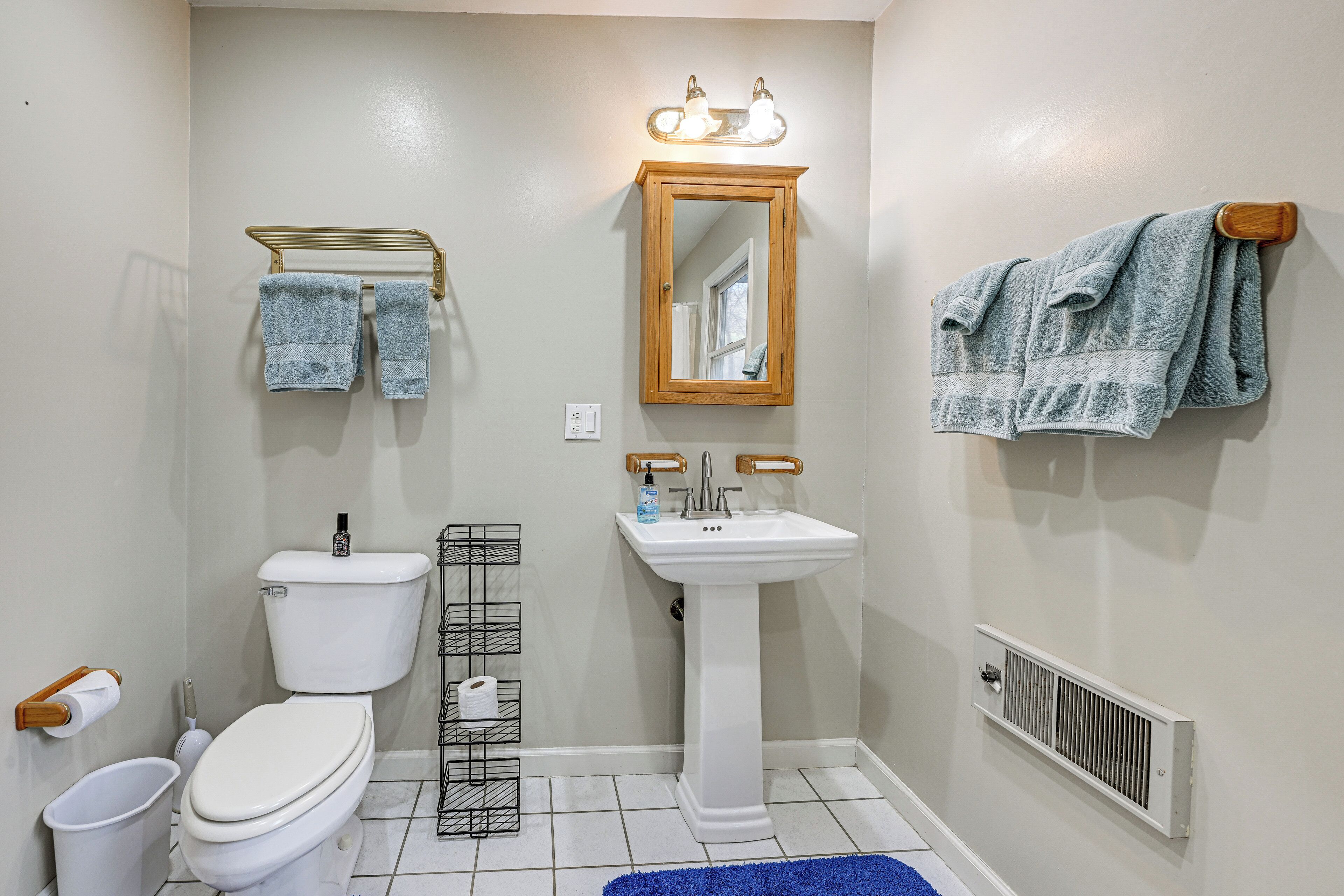 A bathroom with a toilet, sink, mirror, and towel rack.