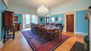 A dining room with a chandelier, wooden chairs, a round table, and a patterned rug. - Historic Chambersburg Home w/ Pool + Game Rooms! (Chambersburg)