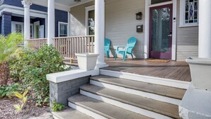 A porch with steps leading to a door, two chairs, and a small garden area. - Stylish Home in Springfield Historic District! (Jacksonville)