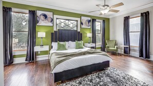 A bedroom with a large bed, a ceiling fan, and a view of the outdoors through the windows. - Stylish Home in Springfield Historic District! (Jacksonville)