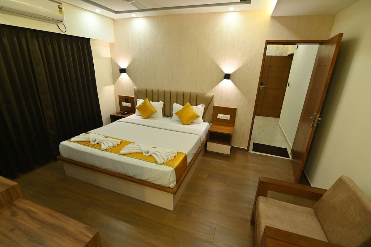 A hotel room with a large bed, two bedside tables with lamps, a wooden floor, and a mirror on the wall.