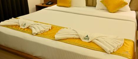 A hotel room with a neatly made bed, a bedside table with a lamp, and a phone.