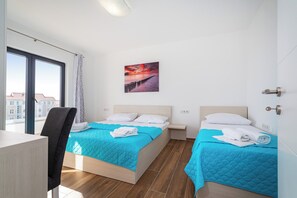 Une chambre d’hôtel avec deux lits, un bureau et une grande fenêtre.