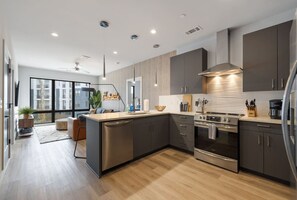A modern kitchen with a central island, stainless steel appliances, and a view to a living area.