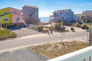 Un barrio residencial frente al mar con casas de varios pisos, cielo despejado y una carretera que lleva a la playa.