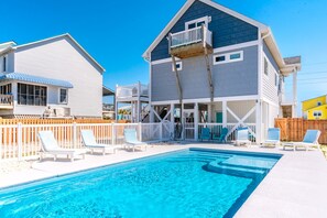 A swimming pool with lounge chairs and a wooden deck.