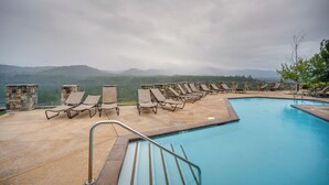 Zona de piscina con sillones de descanso y vistas a las montañas.
