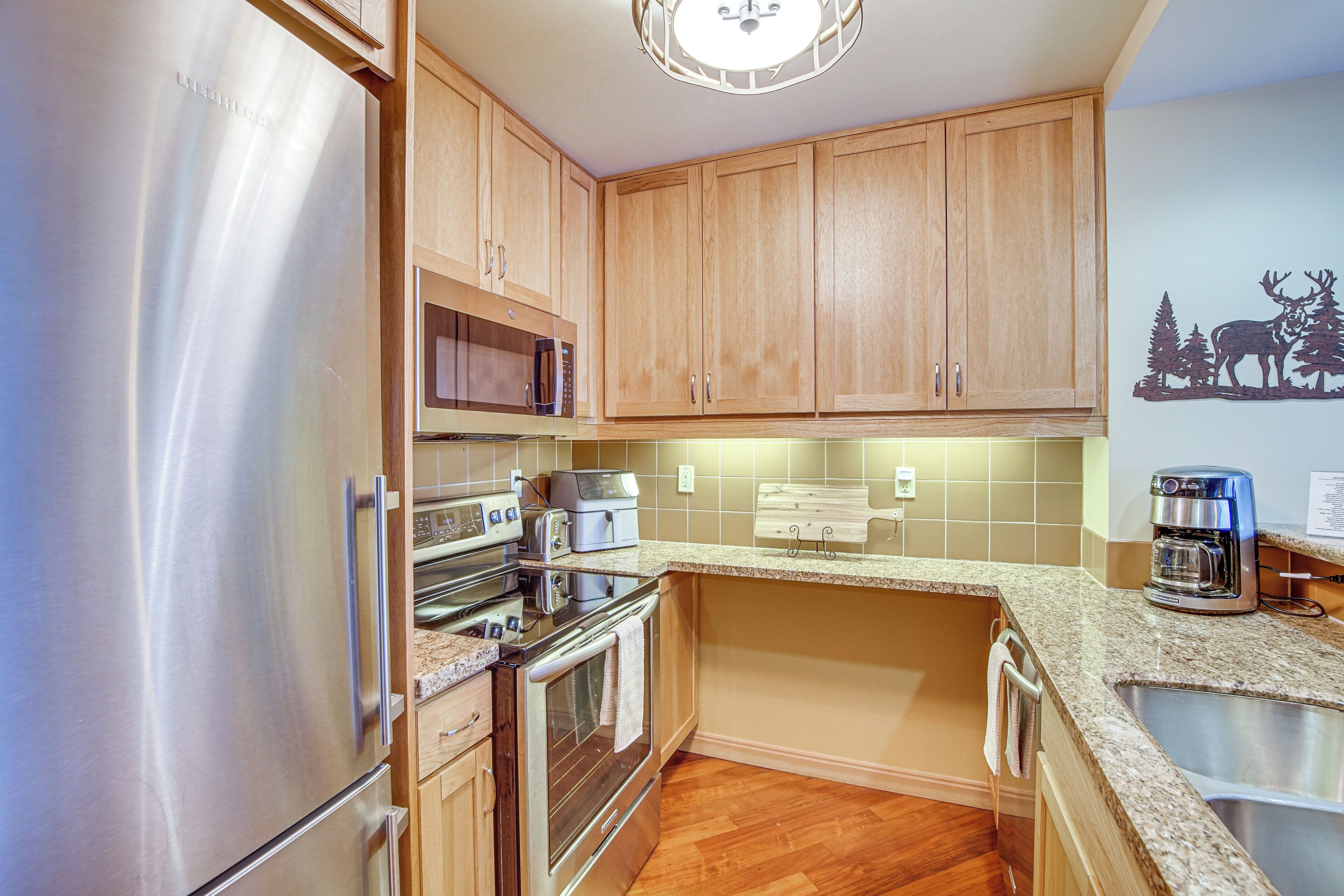A kitchen with wooden cabinets, stainless steel appliances, a microwave, a toaster, and a coffee maker.