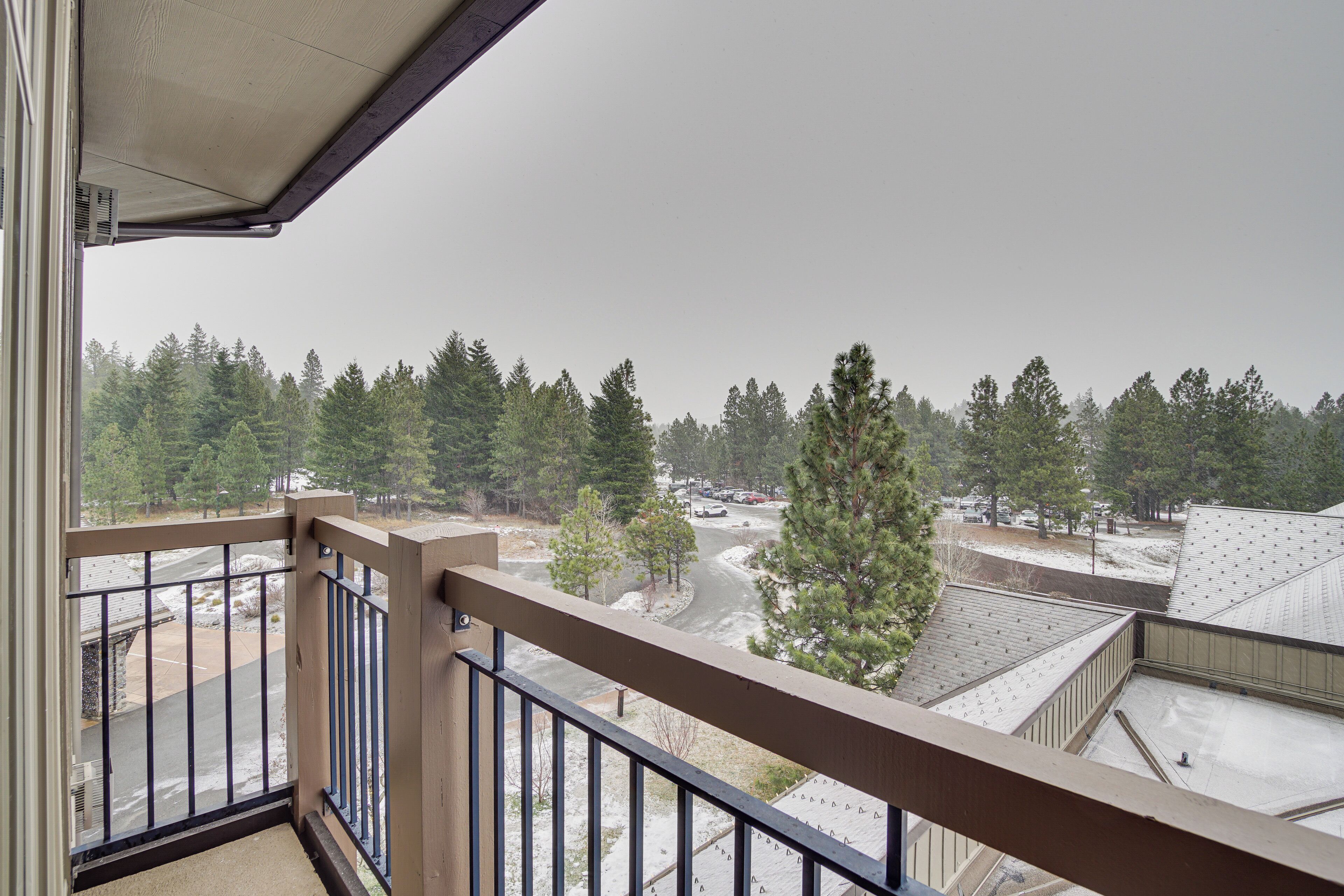A balcony with a view of a parking area and trees.