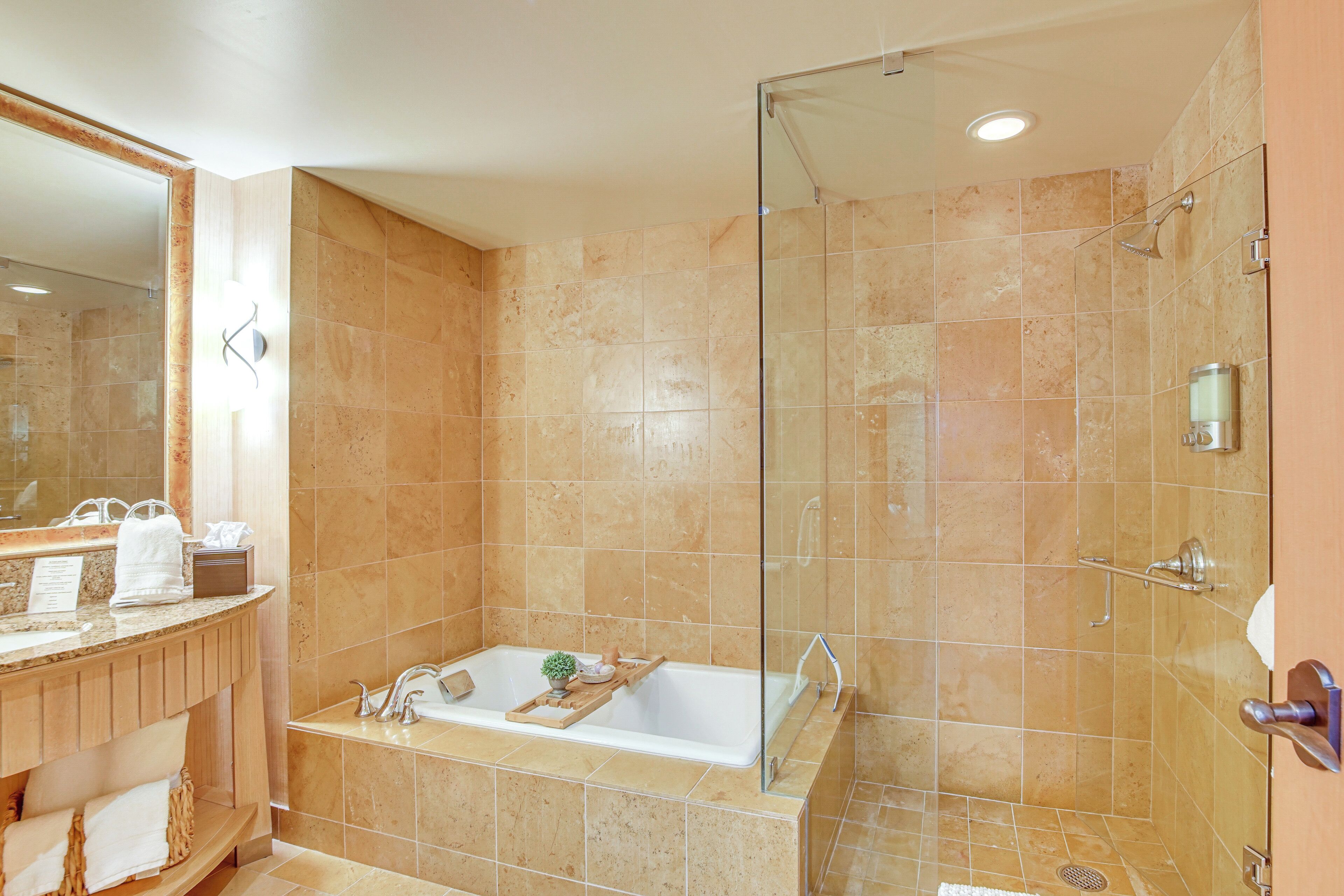 A modern bathroom with a glass-enclosed shower, a freestanding bathtub, and a vanity with a mirror and towel rack.