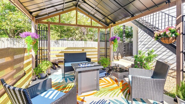 Un patio cubierto con mobiliario de mimbre, una chimenea y macetas colgantes.