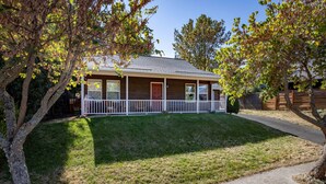 A single-story house with a front porch, a well-maintained lawn, and a wooden fence. - Devon Court 2 Bedroom Home by RedAwning (Hood River)