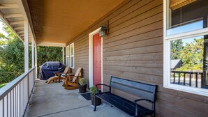 A covered porch with a wooden bench, Adirondack chairs, and a grill. - Devon Court 2 Bedroom Home by RedAwning (Hood River)