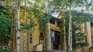 A building with a stone facade, a central staircase, and surrounding trees. - Townhome With Ski-in Access Near Pool And Spa by The Woodrun V Townhouses by RedAwning (Snowmass Village)