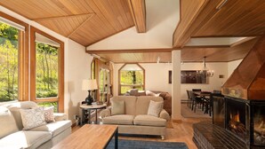 A cozy living room with a fireplace, wooden ceiling, and large windows offering a view of the outdoors. - Townhome With Ski-in Access Near Pool And Spa by The Woodrun V Townhouses by RedAwning (Snowmass Village)