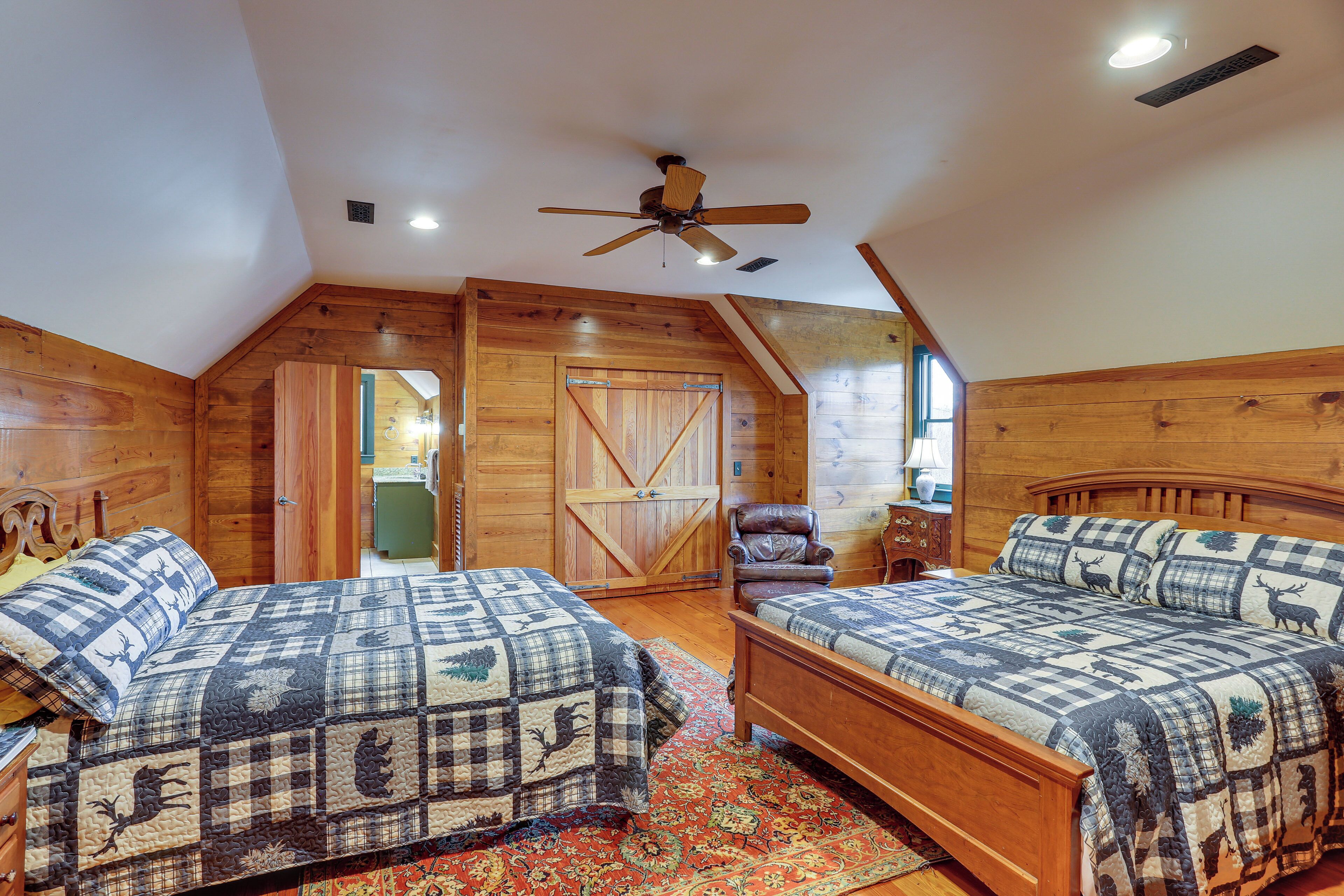 A bedroom with two wooden beds, a ceiling fan, and a rustic wooden interior.