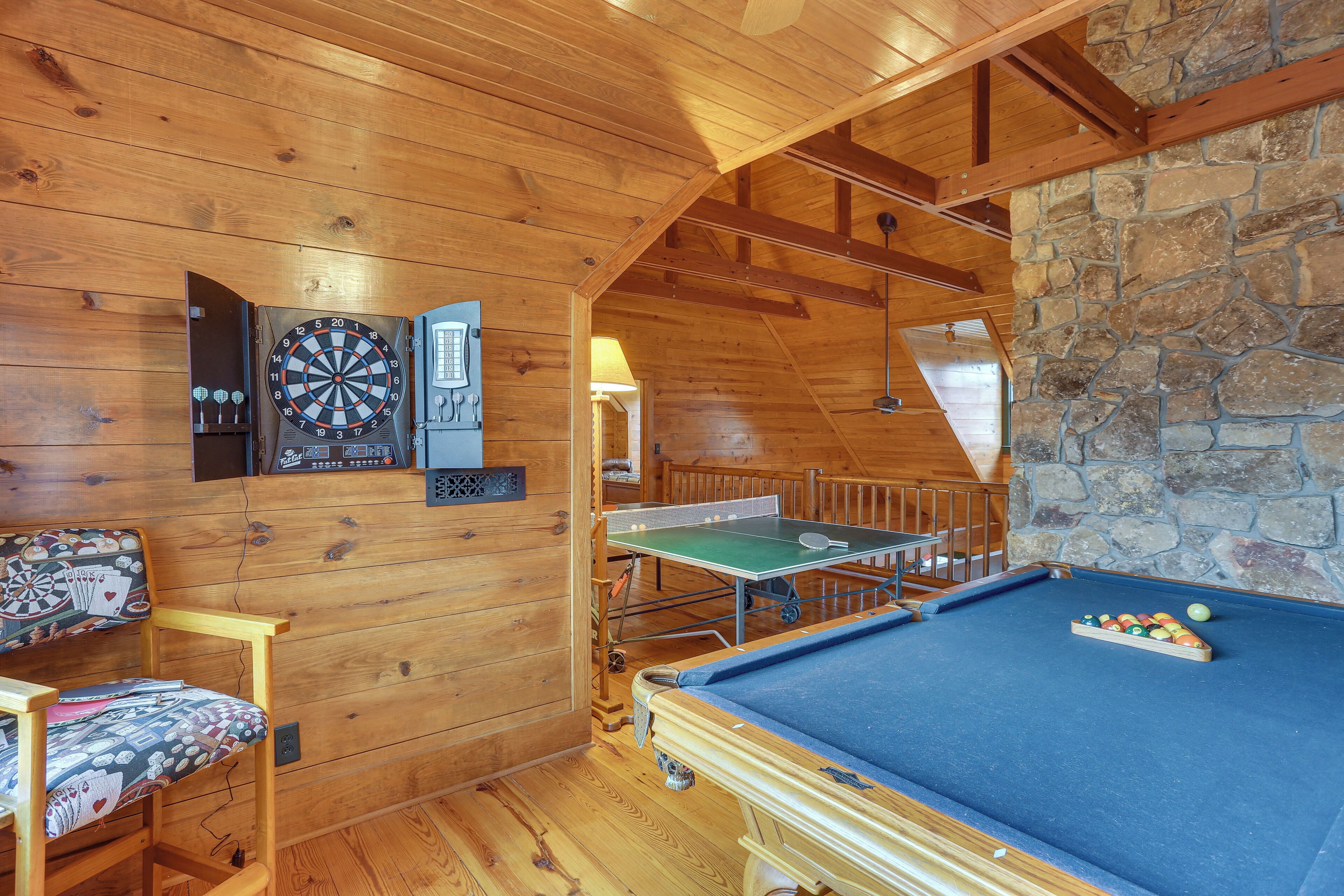 Ein Holzraum mit Billardtisch, Dartscheibe und Tischtennisplatte.