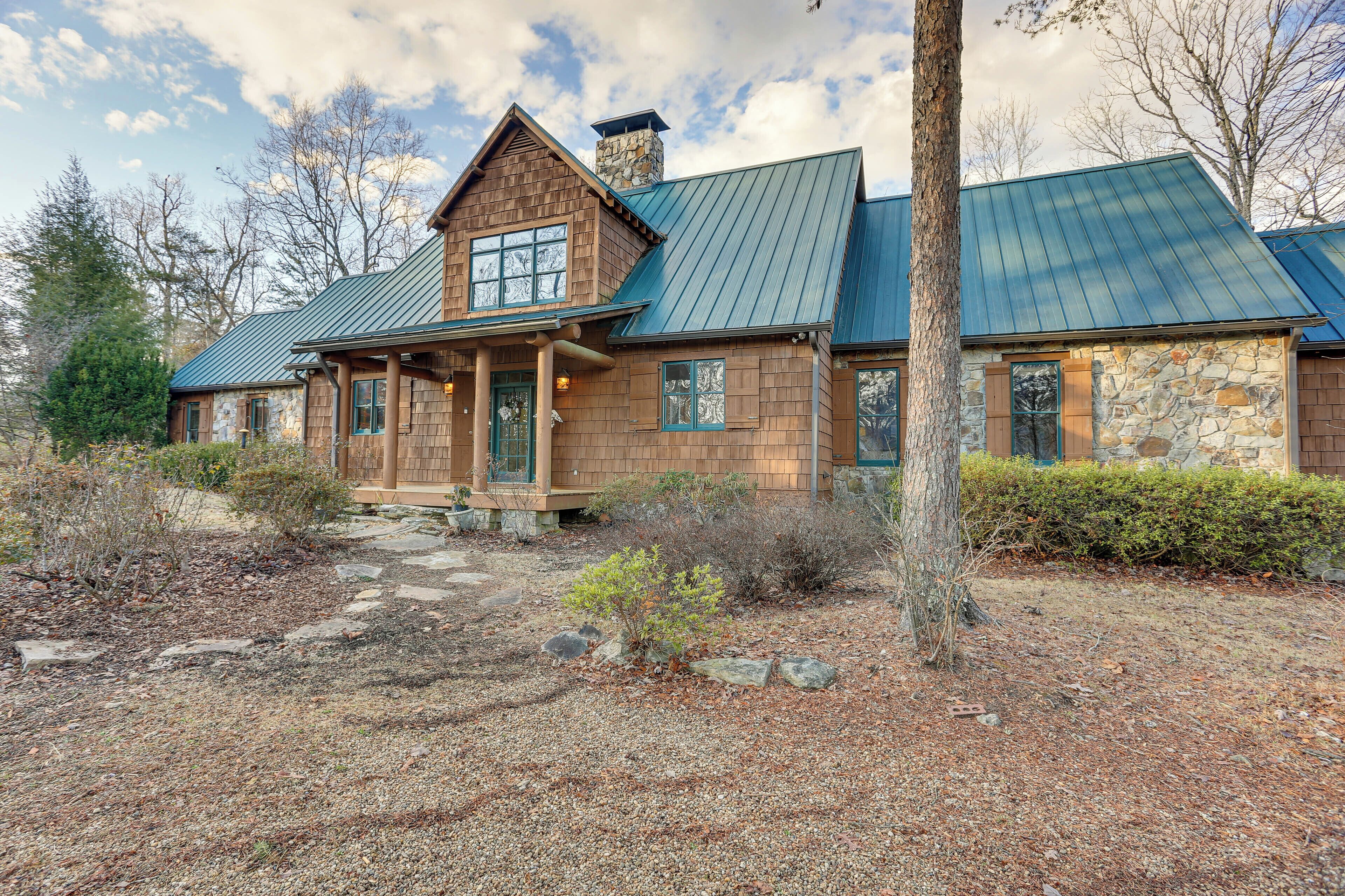 A rustic log cabin with a stone chimney, a metal roof, and a stone exterior.
