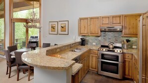 A modern kitchen with a granite countertop, wooden cabinets, a built-in oven, and a hanging light fixture. - Contemporary Townhome With Ski-in/ski-out Access by The Woodrun V Townhouses by RedAwning (Snowmass Village)