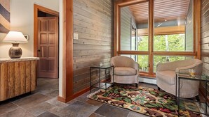 A wooden interior with a large window, a door, and a small table with a lamp. - Contemporary Townhome With Ski-in/ski-out Access by The Woodrun V Townhouses by RedAwning (Snowmass Village)