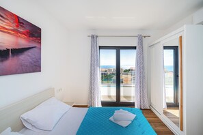 Een hotelkamer met een bed, stadszicht en een balkon met gordijnen.