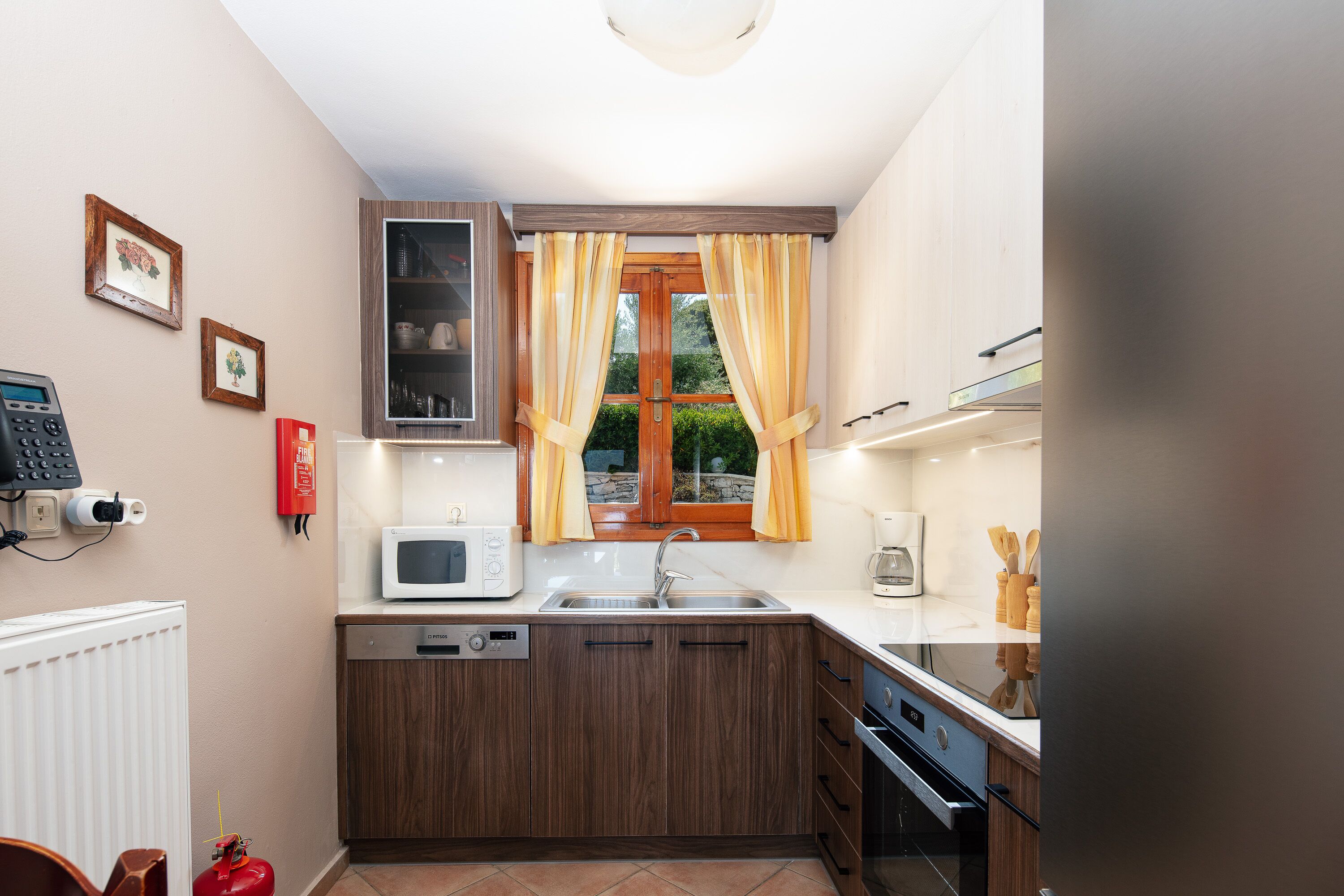 Une cuisine compacte équipée d’un four à micro-ondes, d’un évier et de meubles de rangement en bois.