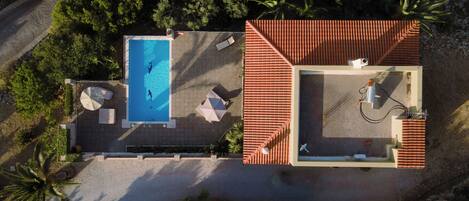 Vista aérea de uma propriedade com piscina, área de estar externa e telhado telhado.