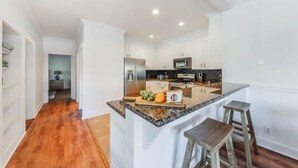 Una cocina moderna con armarios blancos, encimera de granito y microondas integrado.