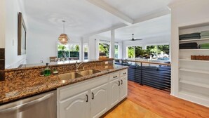 Una cocina moderna con encimeras de granito, armarios blancos y vistas al exterior.