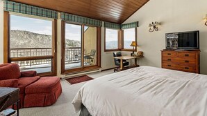 Camera da letto con un letto grande, una scrivania, una sedia, una televisione e vista sull'esterno.